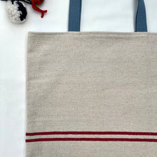Load image into Gallery viewer, Tote bag. Heavyweight natural woven canvas with two horizontal red stripes. Lined with an ex-designer striped cotton shirting fabric.