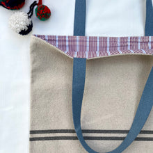 Load image into Gallery viewer, Tote bag. Heavyweight natural woven canvas with two horizontal blue grey stripes. Lined with a beautiful striped cotton shirting fabric.