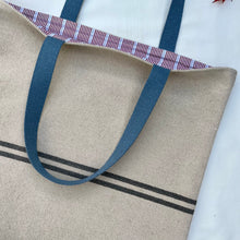 Load image into Gallery viewer, Tote bag. Heavyweight natural woven canvas with two horizontal blue grey stripes. Lined with a beautiful striped cotton shirting fabric.