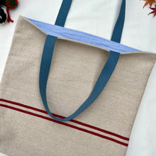 Load image into Gallery viewer, Tote bag. Heavyweight natural woven canvas with two horizontal red stripes. Lined with an ex-designer striped cotton shirting fabric.