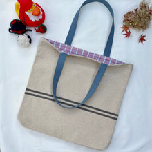 Load image into Gallery viewer, Tote bag. Heavyweight natural woven canvas with two horizontal blue grey stripes. Lined with a beautiful striped cotton shirting fabric.
