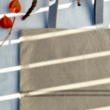 Load image into Gallery viewer, Tote bag. Heavyweight natural woven canvas with two horizontal sand-coloured stripes. Lined with a striped cotton shirting fabric.