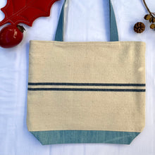 Load image into Gallery viewer, Tote bag. Heavyweight natural woven canvas with two horizontal blue stripes and light blue cotton denim bottom.
