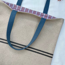 Load image into Gallery viewer, Tote bag. Heavyweight natural woven canvas with two horizontal blue grey stripes. Lined with a beautiful striped cotton shirting fabric.
