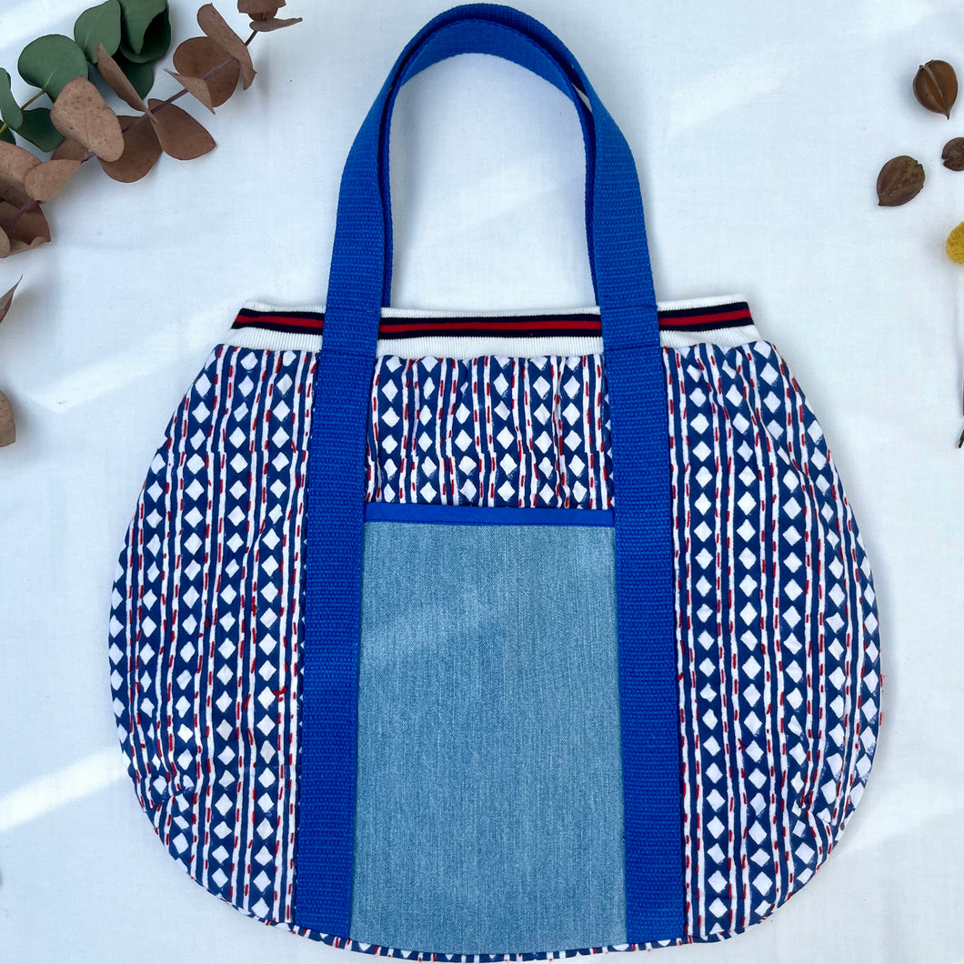 Block print bowling bag. Blue and white cotton print with red visible stitch. Red, navy blue and white knit cuff.