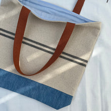 Load image into Gallery viewer, Tote bag. Heavyweight natural woven canvas with two horizontal blue grey stripes and light blue cotton denim bottom.
