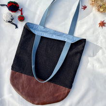 Load image into Gallery viewer, Tote bag. Luxurious fine wool fabric with small blue and brown squares and upcycled chocolate brown leather round bottom.
