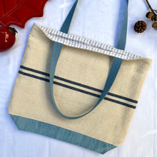 Load image into Gallery viewer, Tote bag. Heavyweight natural woven canvas with two horizontal blue stripes and light blue cotton denim bottom.
