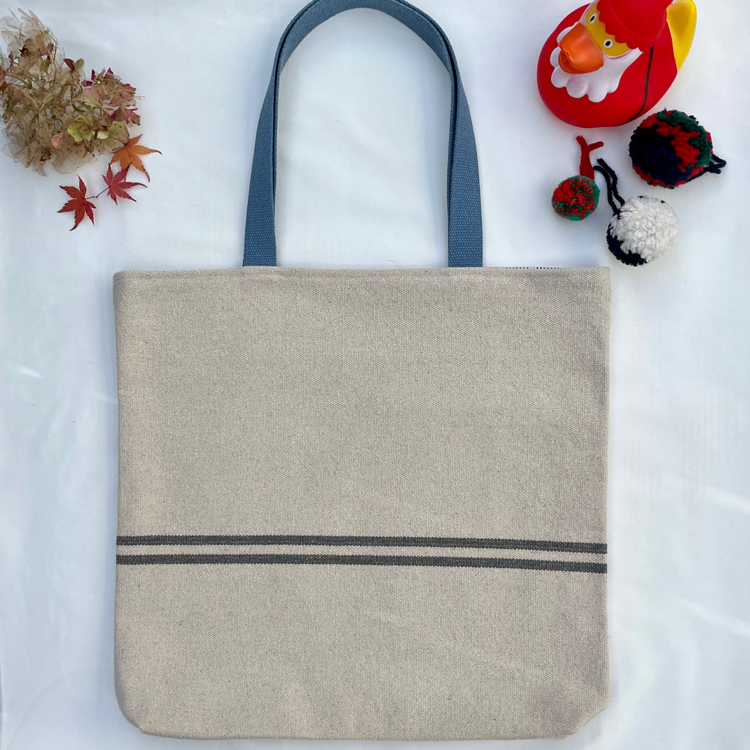 Tote bag. Heavyweight natural woven canvas with two horizontal blue grey stripes. Lined with a beautiful striped cotton shirting fabric.