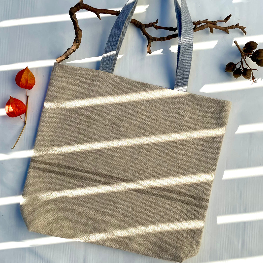 Tote bag. Heavyweight natural woven canvas with two horizontal sand-coloured stripes. Lined with a striped cotton shirting fabric.