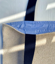 Load image into Gallery viewer, Tote bag. Heavyweight natural woven canvas with two horizontal blue stripes. Lined with a striped cotton shirting fabric.
