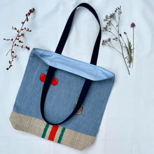 Load image into Gallery viewer, Unique tote bag. Light blue denim with embroidered patches and a vintage grain sack bottom.
