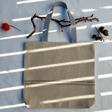 Load image into Gallery viewer, Tote bag. Heavyweight natural woven canvas with two horizontal sand-coloured stripes. Lined with a striped cotton shirting fabric.
