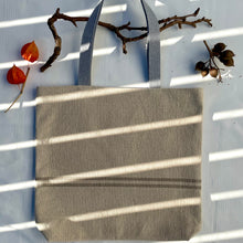 Load image into Gallery viewer, Tote bag. Heavyweight natural woven canvas with two horizontal sand-coloured stripes. Lined with a striped cotton shirting fabric.
