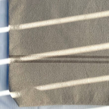 Load image into Gallery viewer, Tote bag. Heavyweight natural woven canvas with two horizontal sand-coloured stripes. Lined with a striped cotton shirting fabric.
