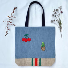 Load image into Gallery viewer, Unique tote bag. Light blue denim with embroidered patches and a vintage grain sack bottom.
