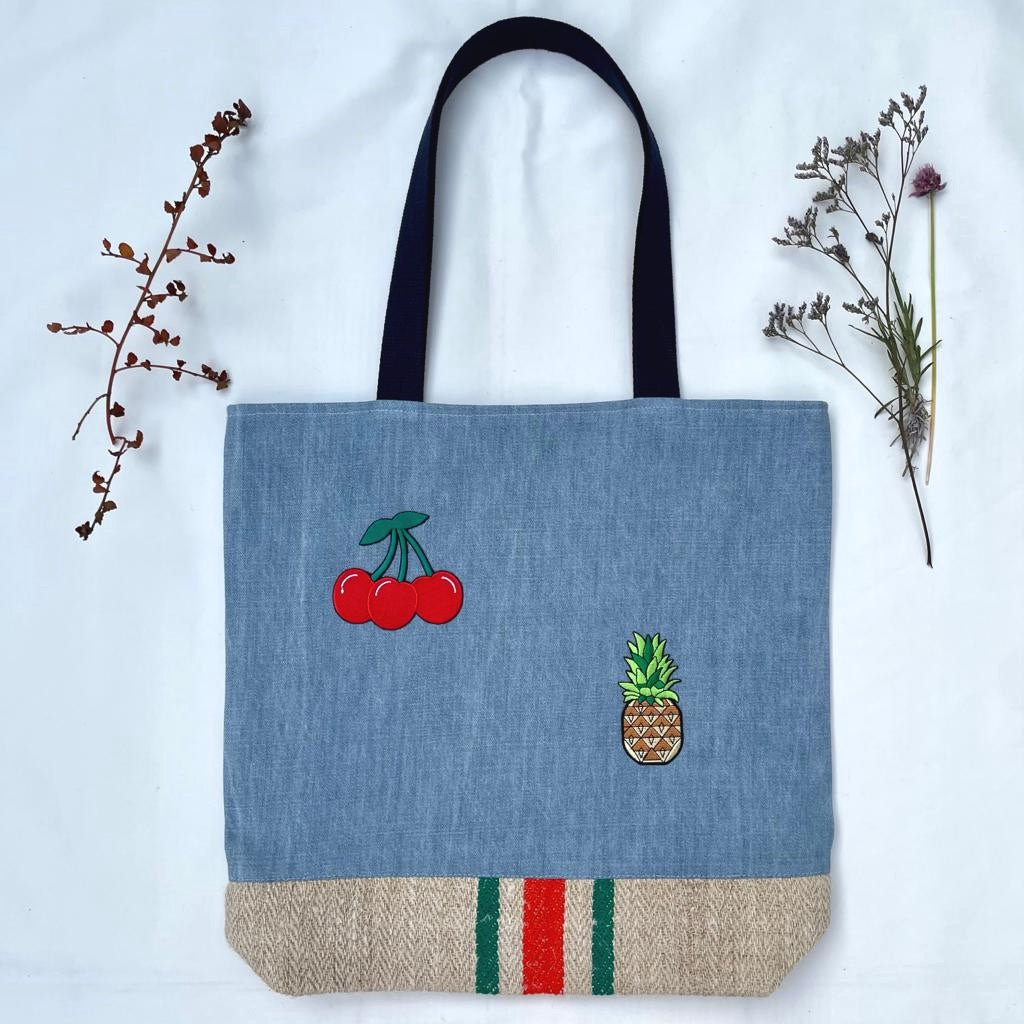 Unique tote bag. Light blue denim with embroidered patches and a vintage grain sack bottom.